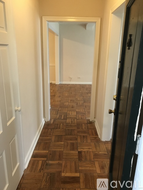A hallway with a wooden floor and white walls.