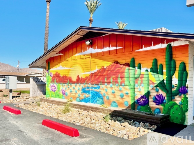 A mural of a desert scene is painted on the side of a building.