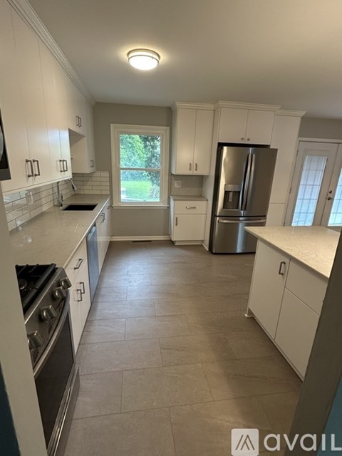A kitchen with white cabinets and a stainless steel refrigerator.