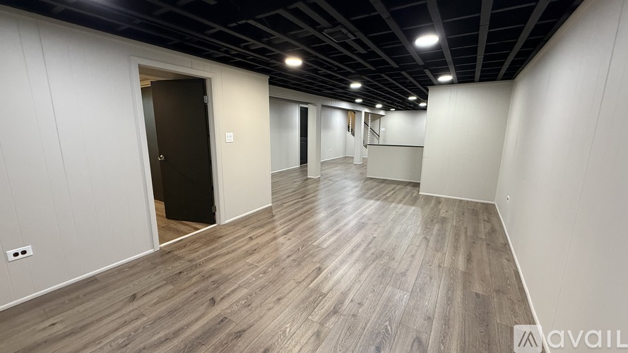 A spacious room with wooden flooring and white walls.