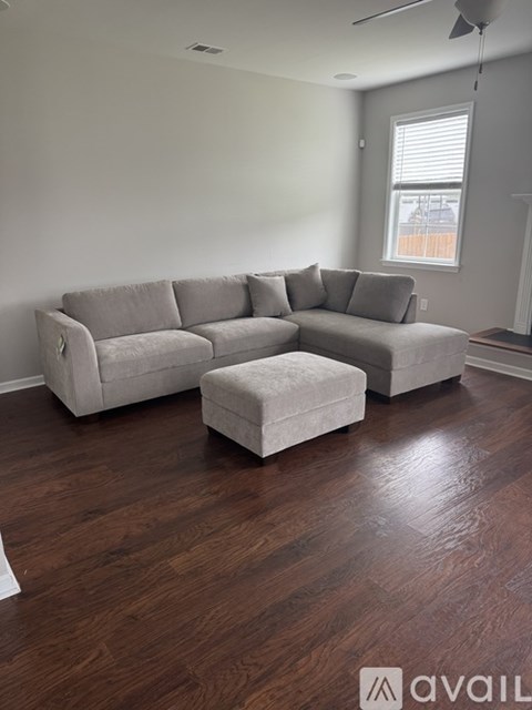 A living room with a grey couch and ottoman.