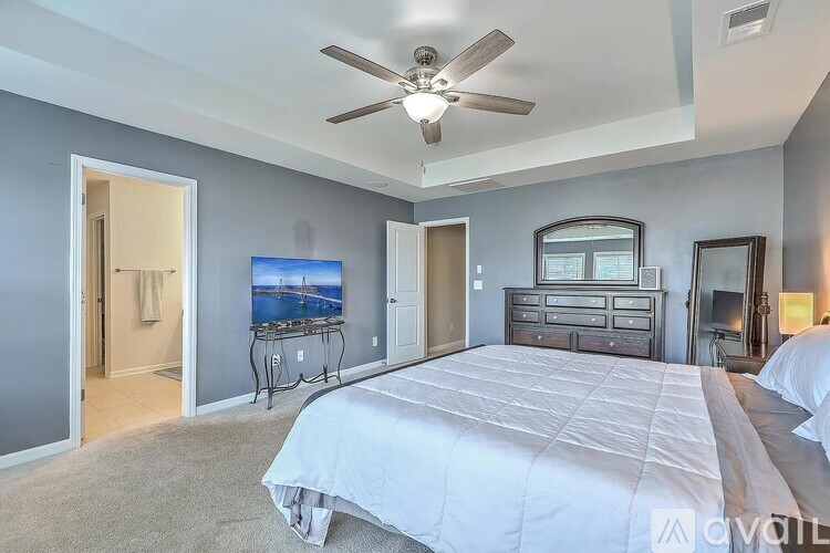 A bedroom with a large bed and a ceiling fan.