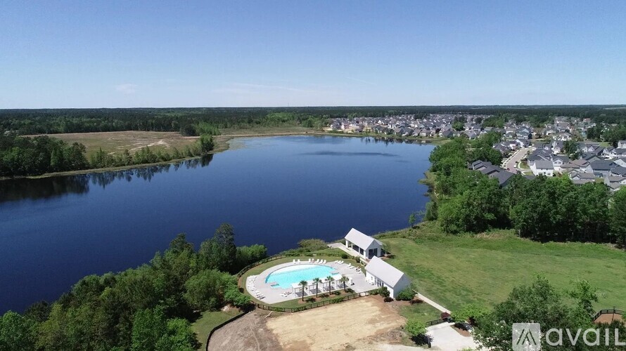 A bird's eye view of a house with a swimming pool and a lake in the background.