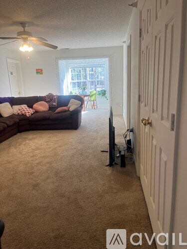 A living room with a brown couch and a ceiling fan.