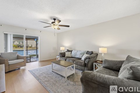 A living room with a grey couch and a glass coffee table.