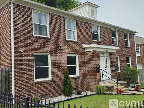 A brick house with a black fence in front.