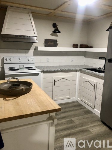 A kitchen with white cabinets and a wooden counter top.
