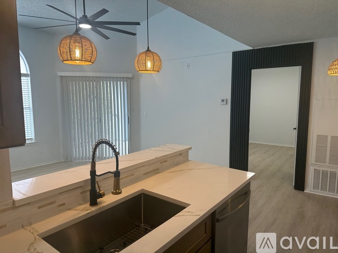 A kitchen with a sink, faucet, and a fan.