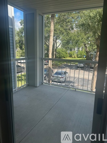 A balcony with a view of a parking lot and trees.