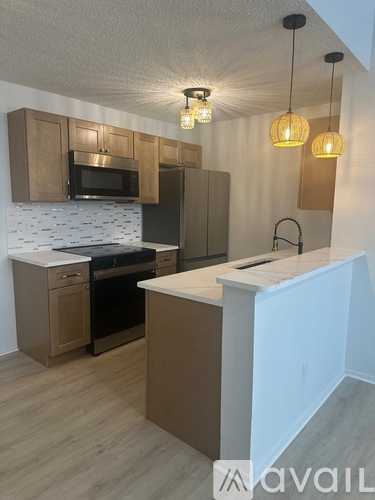 A kitchen with brown cabinets and a white backsplash.