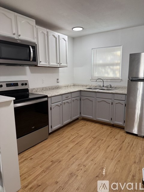 A kitchen with wooden floors and white cabinets.