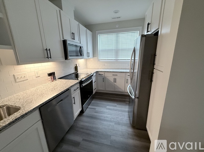 A kitchen with white cabinets and a black fridge.