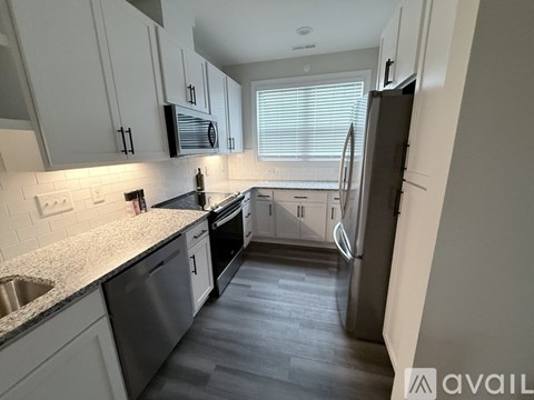 A kitchen with white cabinets and a black fridge.