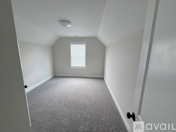 A room with a carpeted floor and a window with blinds.