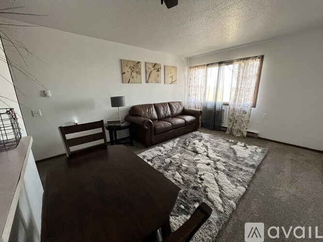 A living room with a brown couch, a wooden table, and a rug.