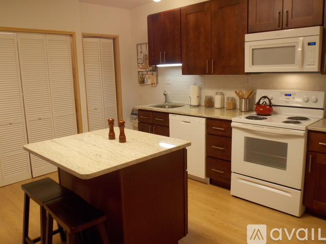 A kitchen with white appliances and wooden cabinets.