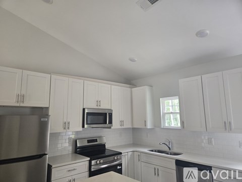 A kitchen with white cabinets and a stainless steel refrigerator.
