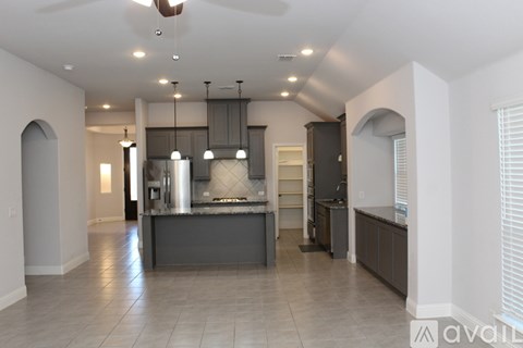 A modern kitchen with a large island and a fan.