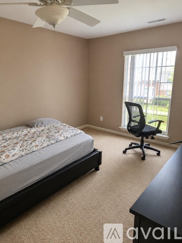A bedroom with a bed, chair, and window.