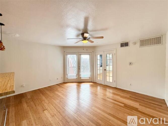 A room with a ceiling fan and wooden flooring.