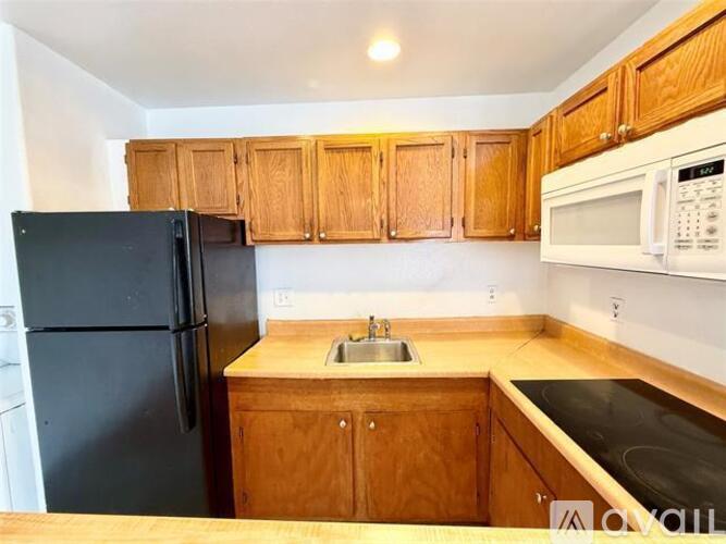 A kitchen with wooden cabinets and a black refrigerator.