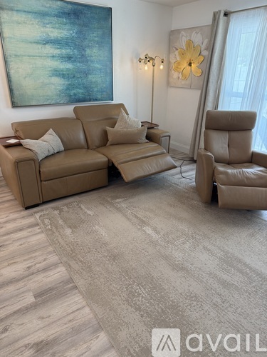 A living room with a brown sofa and a grey carpet.