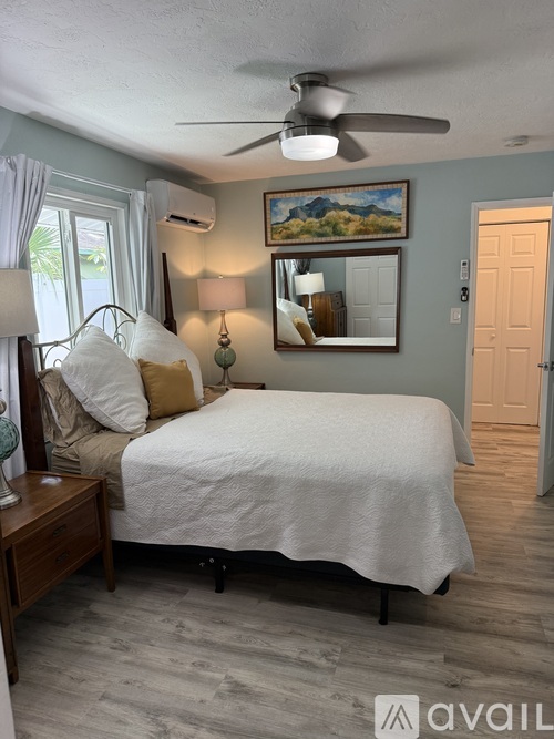 A bedroom with a bed, nightstand, and a painting on the wall.