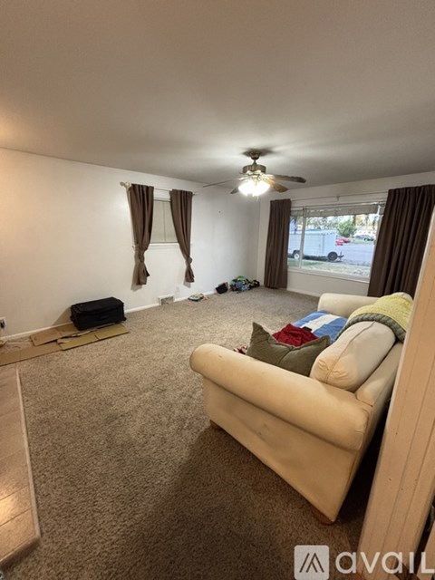 A living room with a beige couch and a ceiling fan.