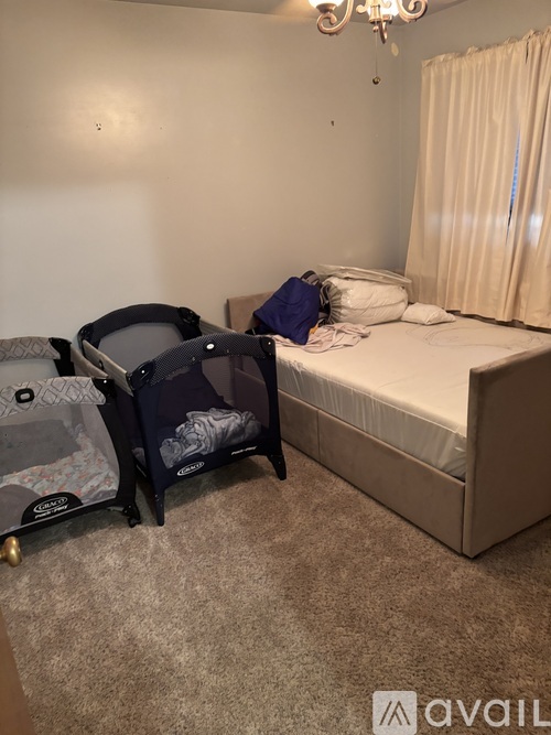 A small bedroom with a single bed, a baby crib, and a carpeted floor.