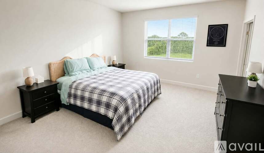 A bedroom with a bed, nightstand, and a window showing a green landscape.