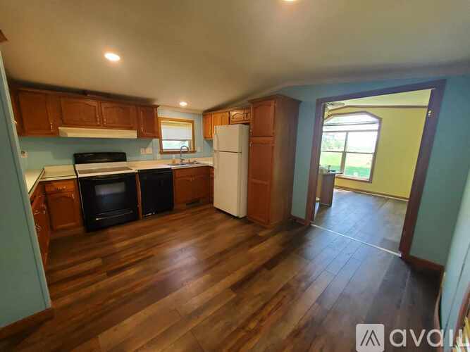 A kitchen with wooden floors and a white refrigerator.
