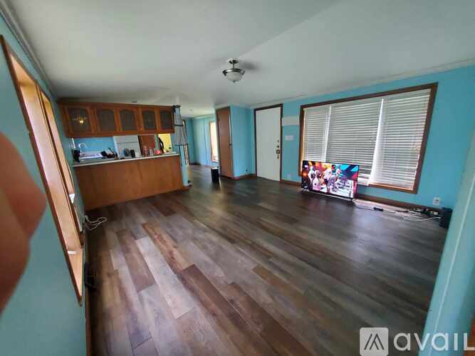 A living room with wooden floors and a television.