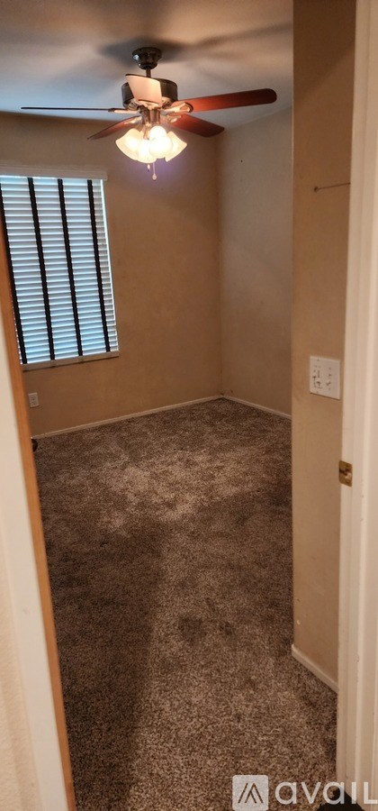 A room with a ceiling fan and a window with blinds.