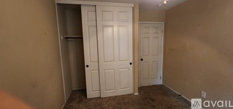 A room with a white door and a brown carpet.