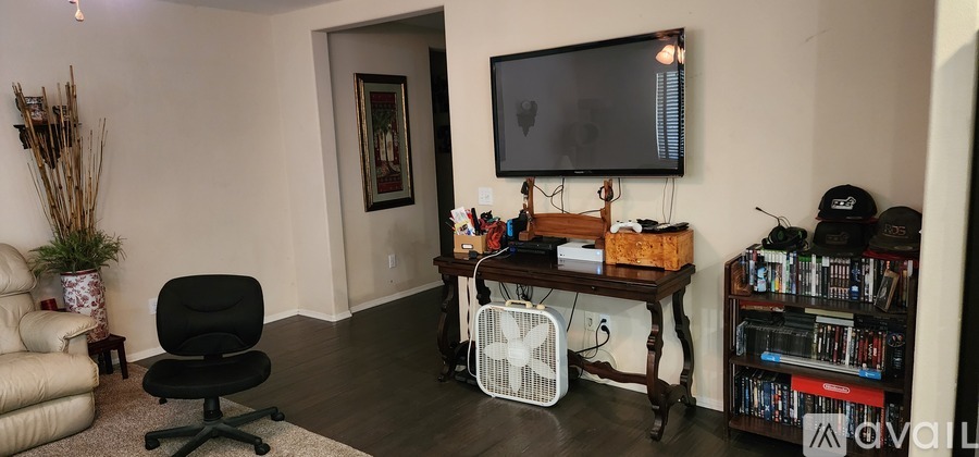 A living room with a black chair and a television on the wall.