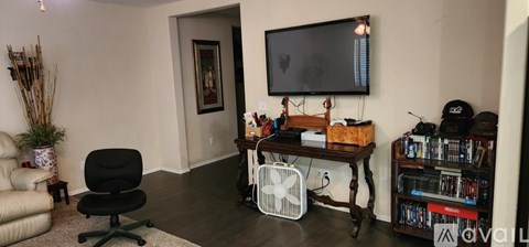 A living room with a black chair and a television on the wall.