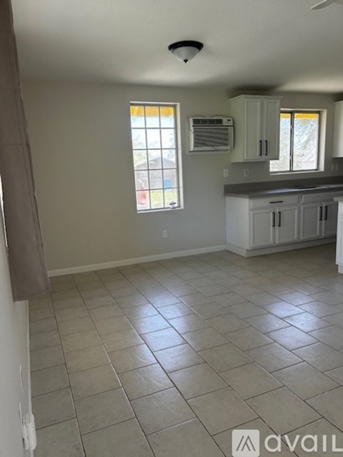 A kitchen with white cabinets and a tiled floor.