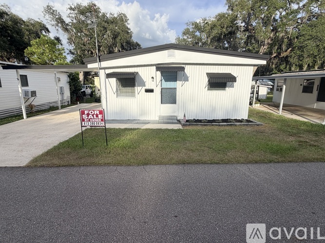A mobile home is for sale with a red sign in front.