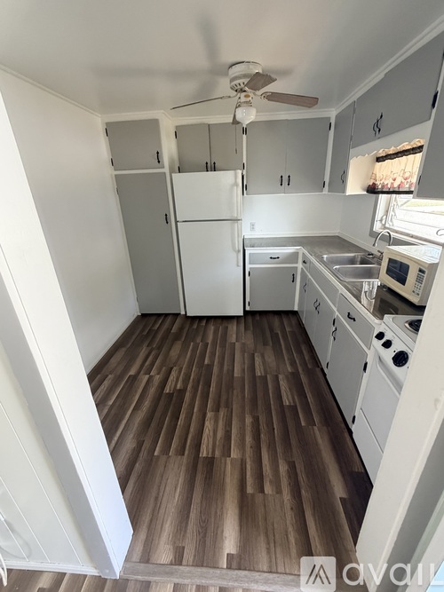 A kitchen with white appliances and wood flooring.