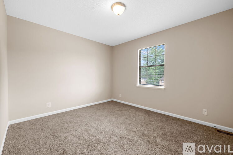 A room with a carpeted floor and a window showing trees outside.