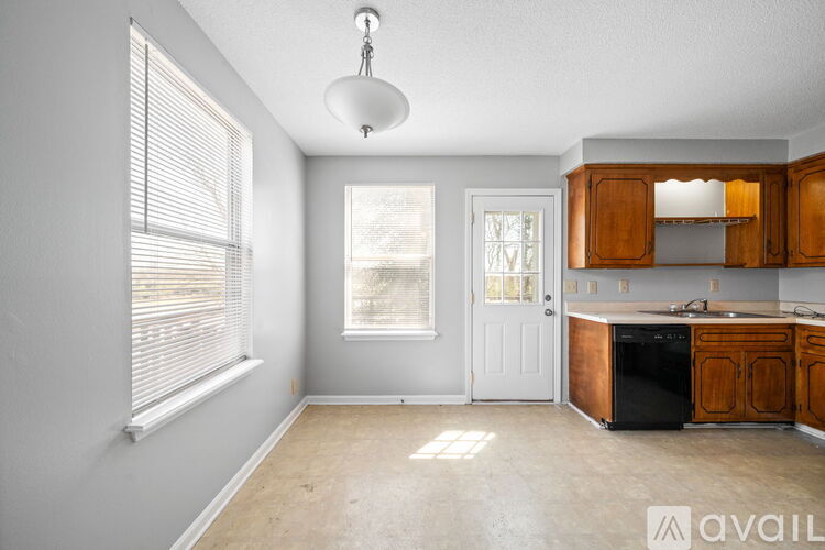 A kitchen with wooden cabinets and a black dishwasher is available for rent.
