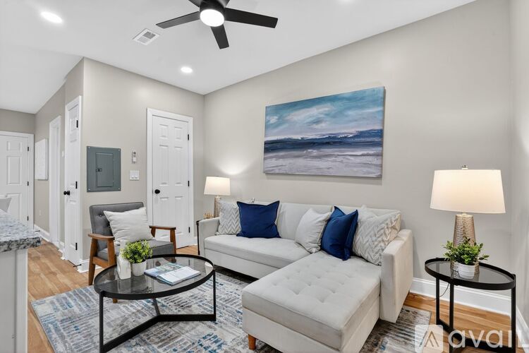 A living room with a white couch, a black coffee table, and a painting on the wall.
