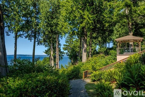 A gazebo sits on a hillside surrounded by trees and shrubbery.