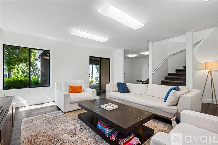 A modern living room with white furniture and a large window.