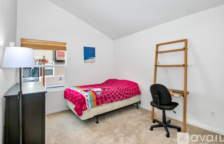 A bedroom with a bed, chair, and a small desk.