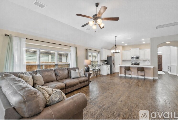 A living room with a brown leather sofa and a ceiling fan.