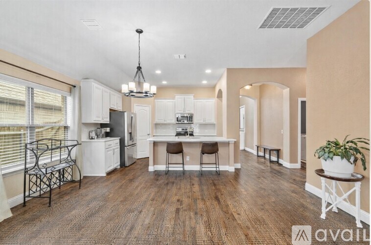 A well-lit kitchen with a dining table and chairs.