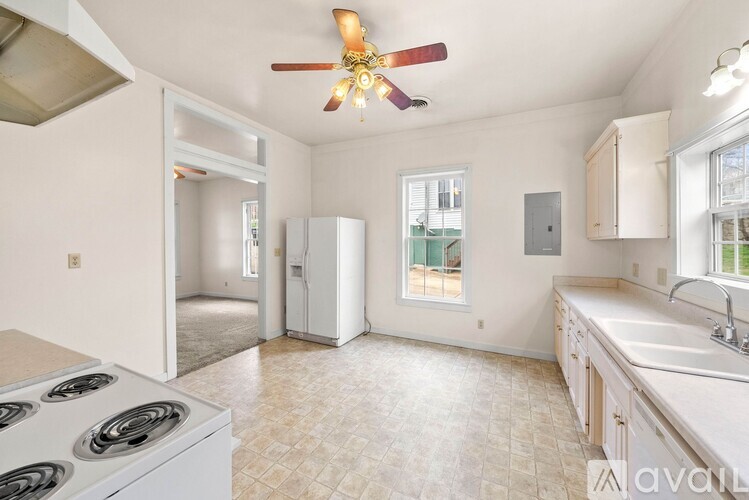 A kitchen with a white stove top oven and a fan ceiling light.