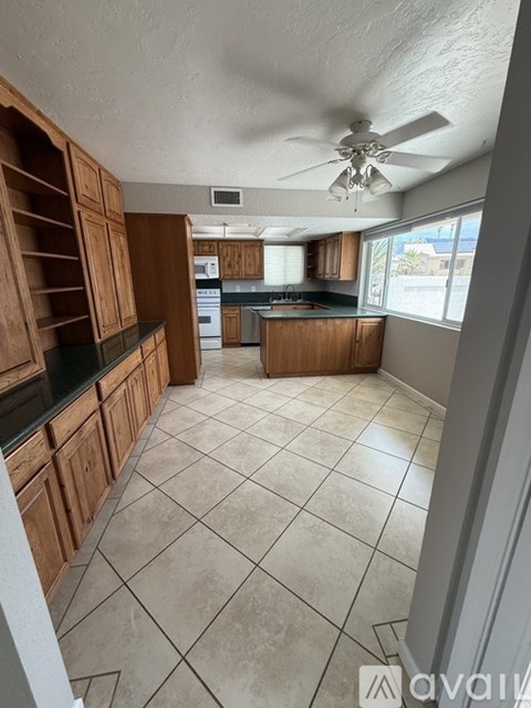 A kitchen with wooden cabinets and a fan on the ceiling.