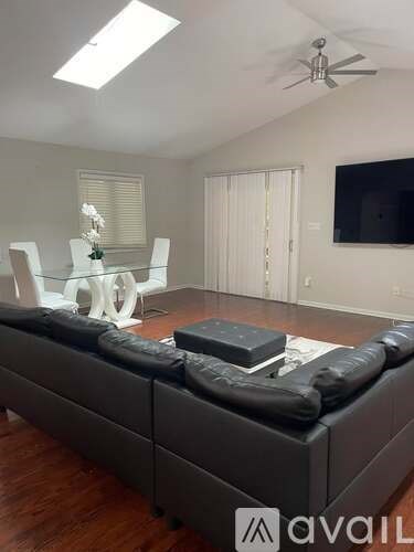 A living room with a grey couch and a television on the wall.
